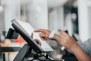 Commerçante utilisant un logiciel de caisse certifié sur écran tactile, ticket de caisse en cours d'impression