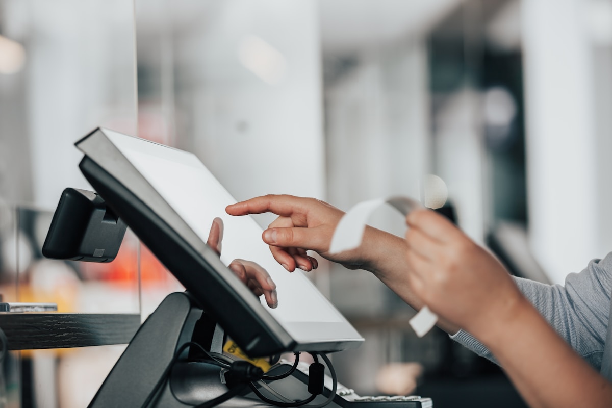 Commerçante utilisant un logiciel de caisse certifié sur écran tactile, ticket de caisse en cours d'impression